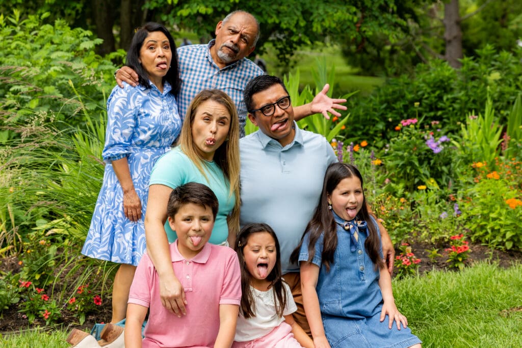 Playful family portrait with grandparents, parents, and kids laughing together in front of colorful flowers – captured by Capture Joy Photography, Northern Virginia family photographer.