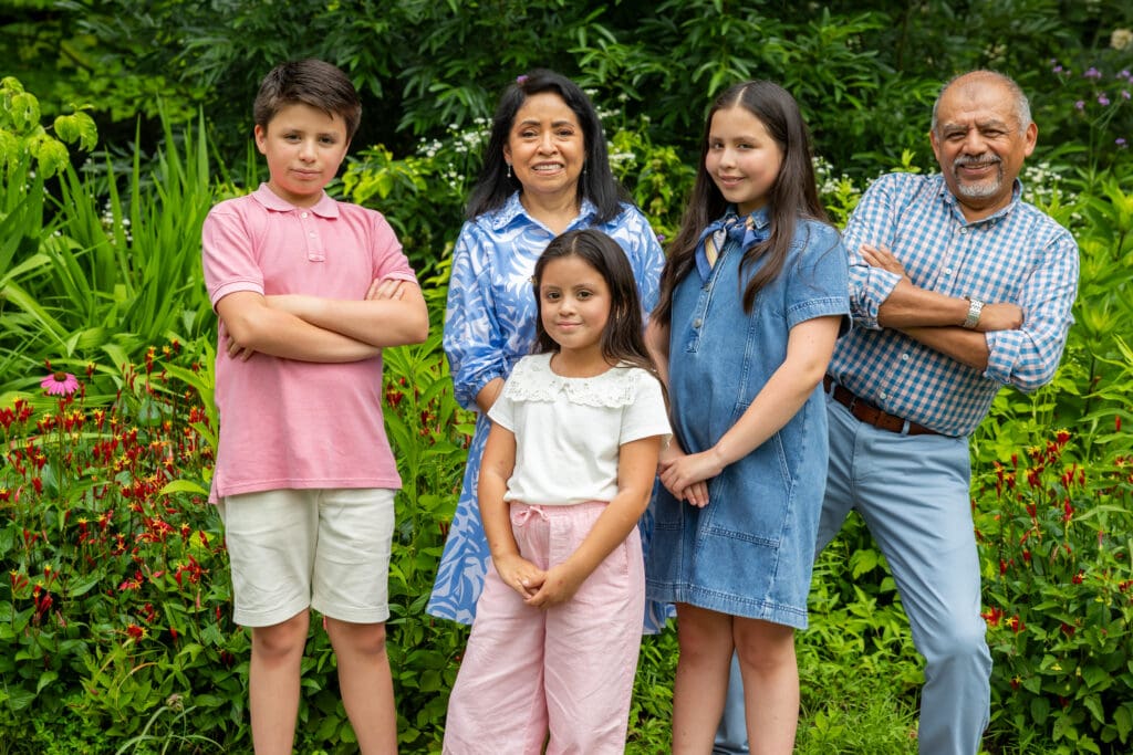 Grandfather with grandchildren and parents smiling together in front of hydrangea bushes – captured by Capture Joy Photography, Northern Virginia family photographer.