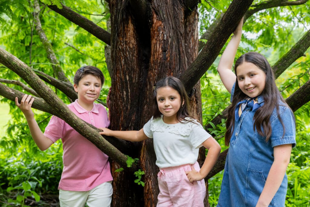Siblings leaning playfully against a tree trunk in Meadowlark Botanical Gardens – captured by Capture Joy Photography, Northern Virginia family photographer.