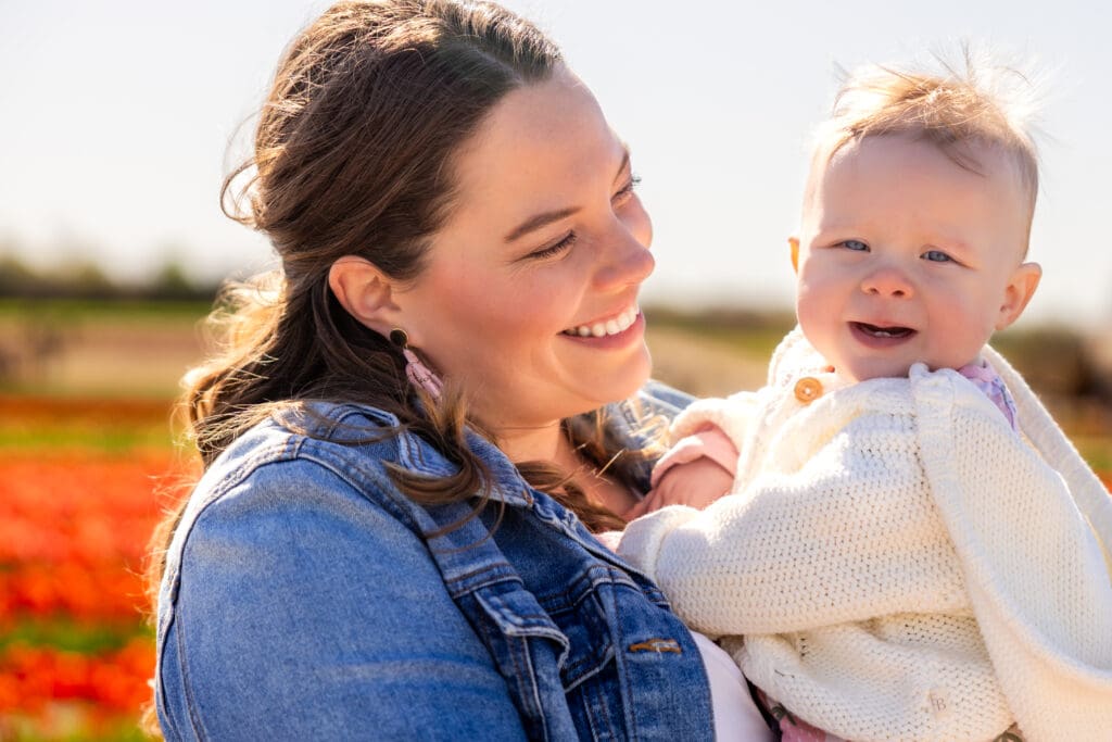 lose-up of mother smiling at baby, their foreheads touching in a tulip field – captured by Capture Joy Photography, Northern Virginia family photographer.